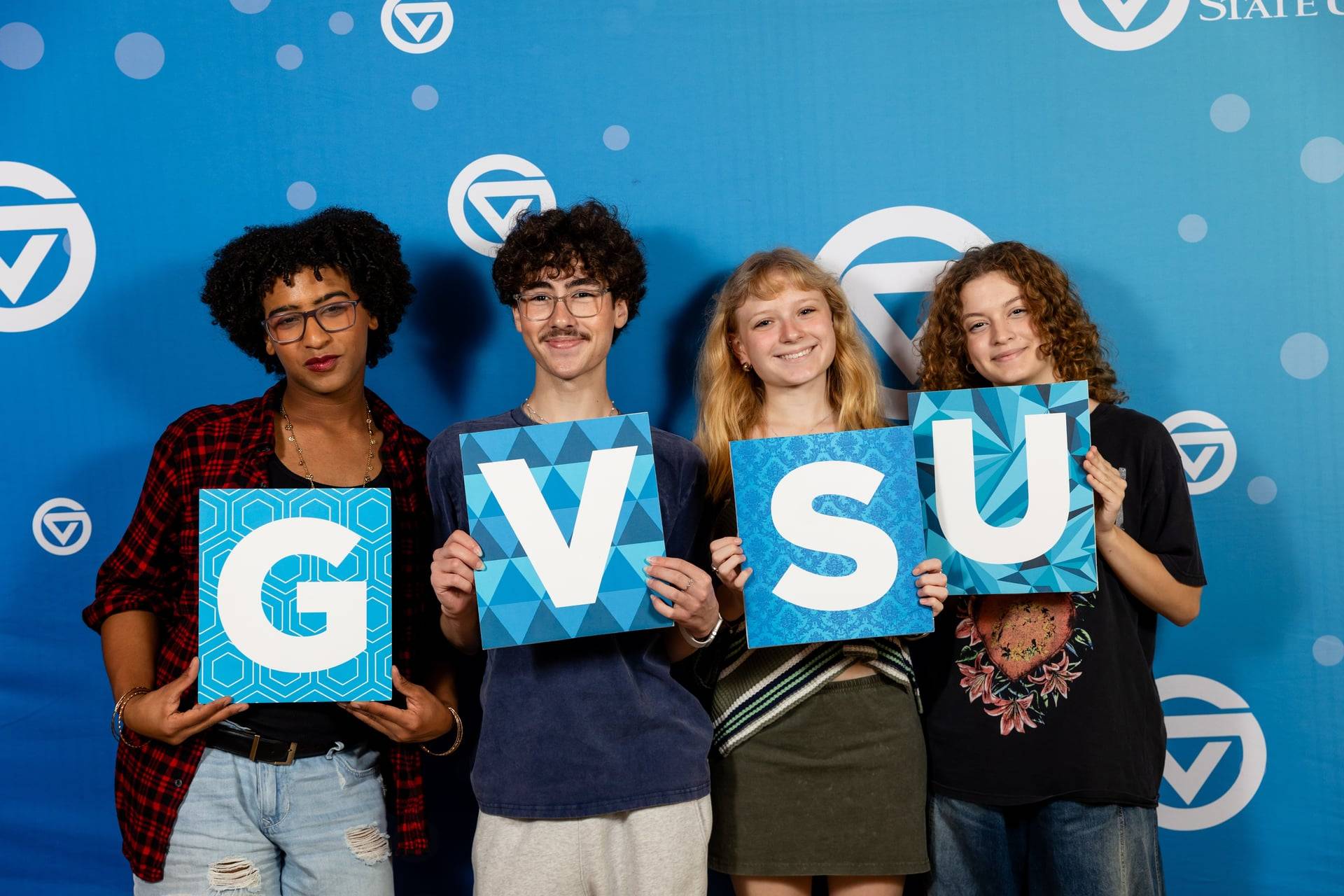 4 students holding first day of classes sign